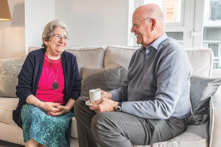 Lady wearing a personal alarm talking to a gentleman on the sofa